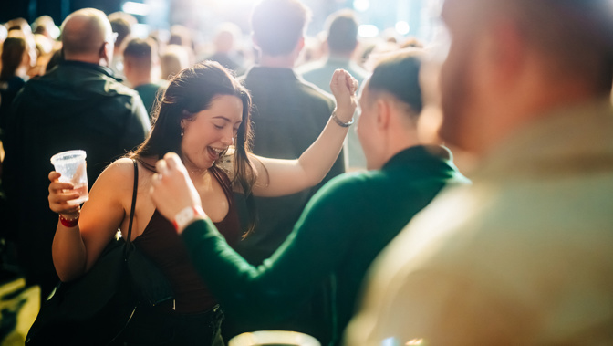 Audience members dancing and enjoying a live music performance in a vibrant festival atmosphere.