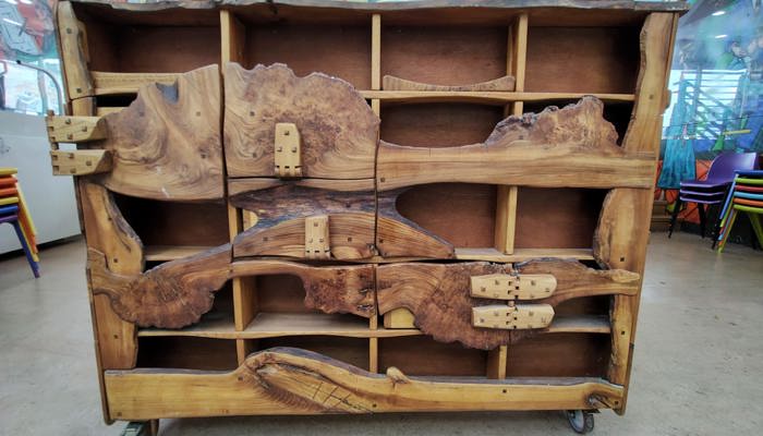 A wooden sculpture with different shelves and compartment, made of different kinds of wood