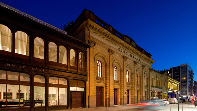Evening view of the historic City Halls building, illuminated against a dark blue sky.