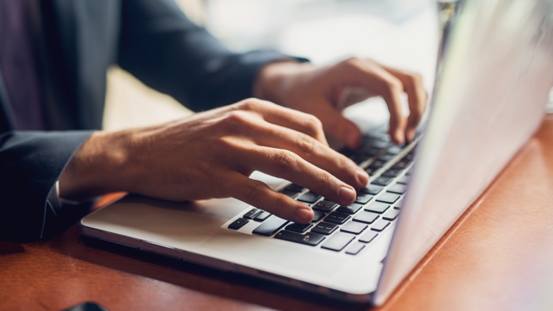 Close up image of hands typing on a laptop keyboard
