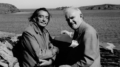 A black and white photo of two people sitting on rocks by the waters edge, Salvador Dali and Dr T J Honeyman