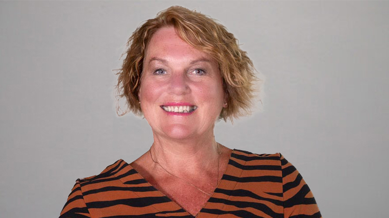 Headshot of a person in a patterned top, facing forward against a neutral background.
