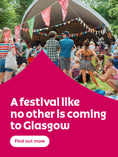 Outdoor festival scene with a crowd gathered under a large tent decorated with colorful bunting. People in summer clothing sit and stand on the grass, surrounded by trees. On the left, bold white text on a magenta background reads ‘A festival like no other is coming to Glasgow’ with a white button below that says ‘Find out more.’
