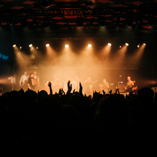Crowd gathered in front of a concert stage illuminated by spotlights and a circular light installation. Provide your feedback on BizChat