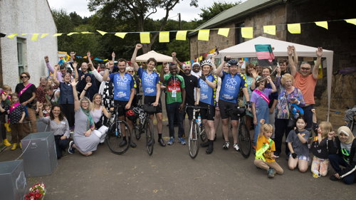 A group of adults some with bikes stand for a group photos smiling 