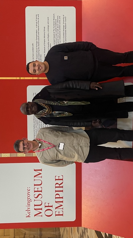 Three people standing in front of interpretation panels in a museum