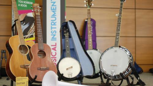 A collection of acoustic guitars and banjos on display in a library