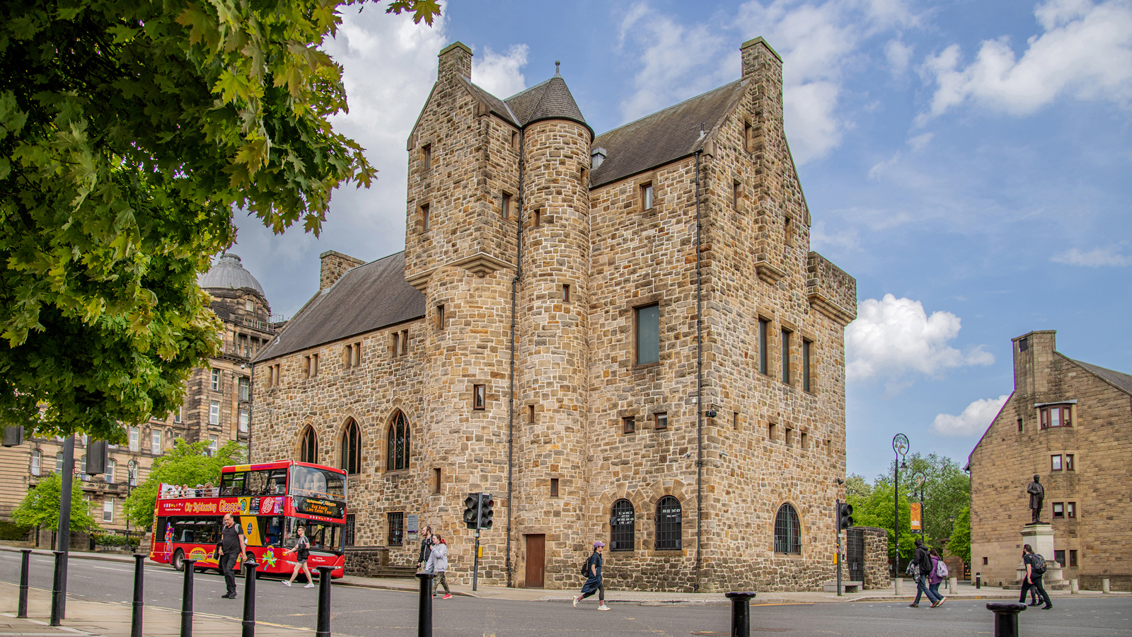 An external photograph of St Mungo Museum Of Religious Life Art with blue sky in the background and a red open top tour bus passing by