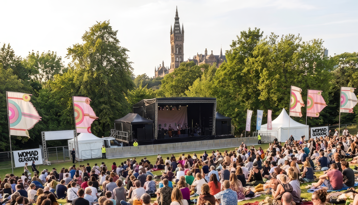 People sit on a grassy slope watching a performance at the WOMAD Glasgow festival.
