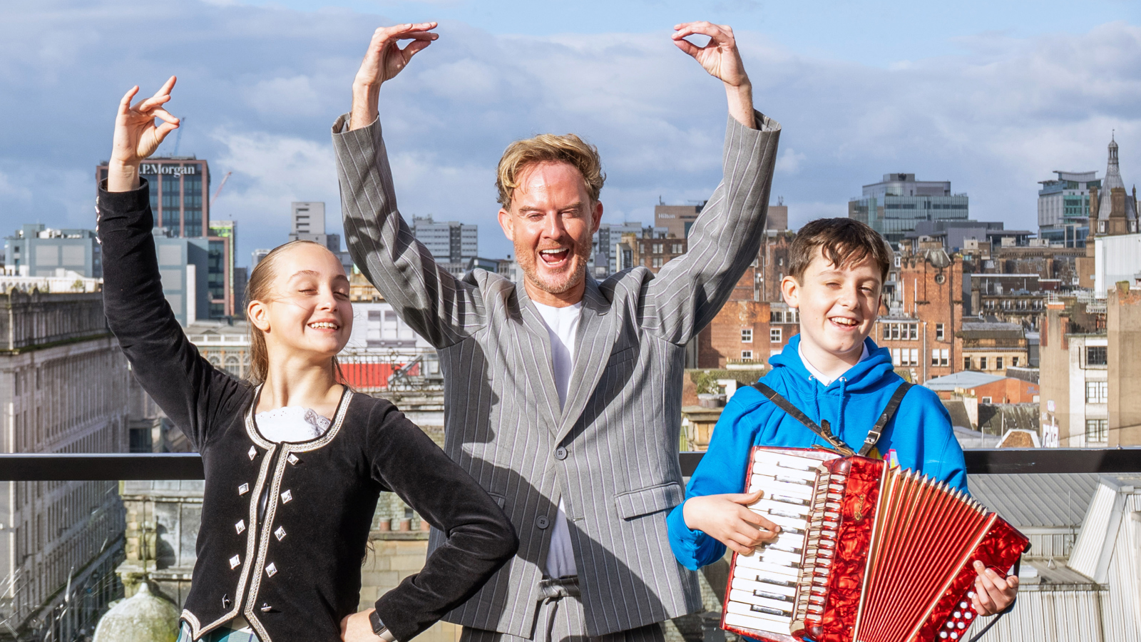 A man and child to the left perform traditional Ceilidh dance poses as a child on the right plays an accordion