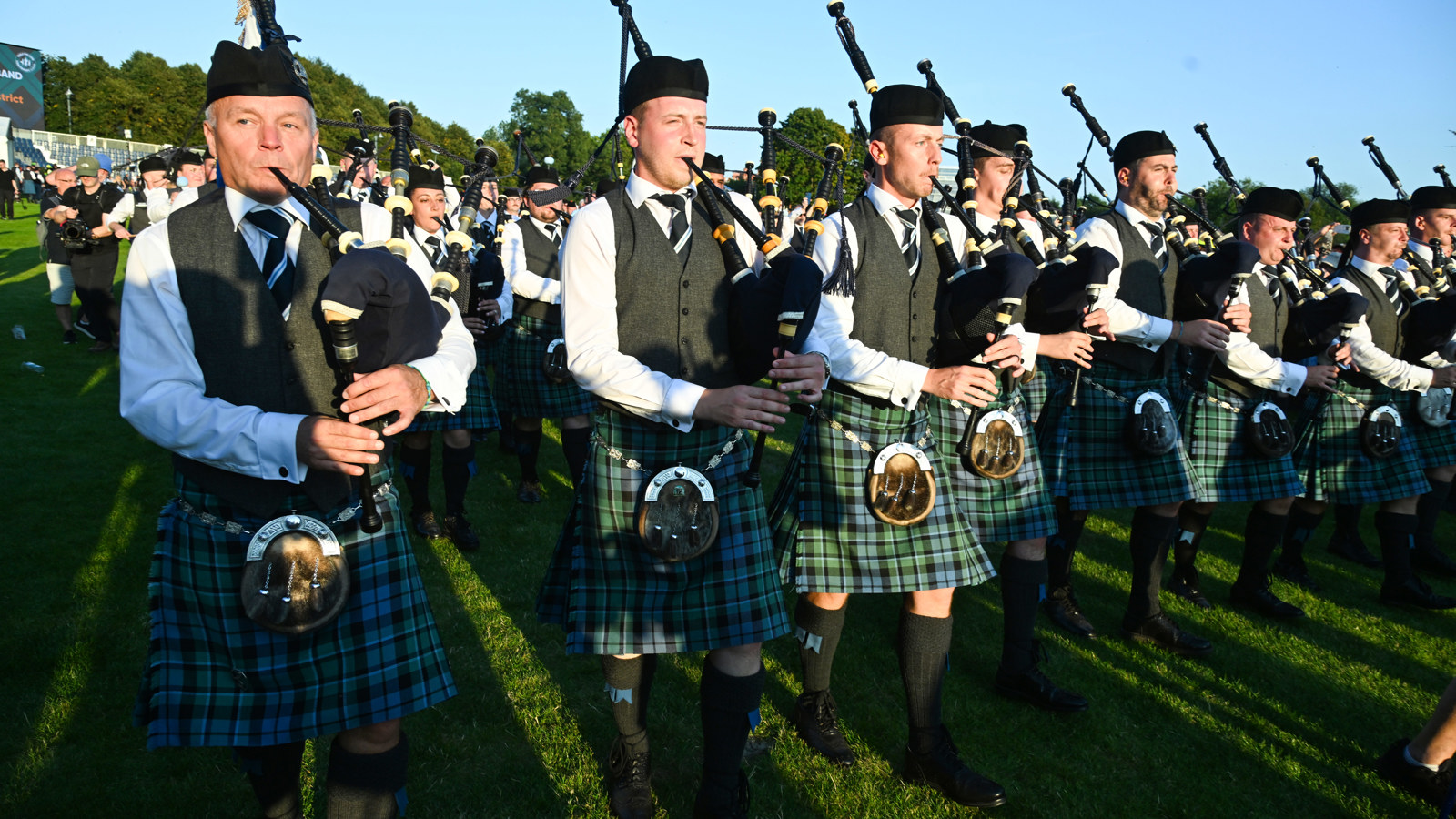 Bagpipers and drummers march together wearing kilts