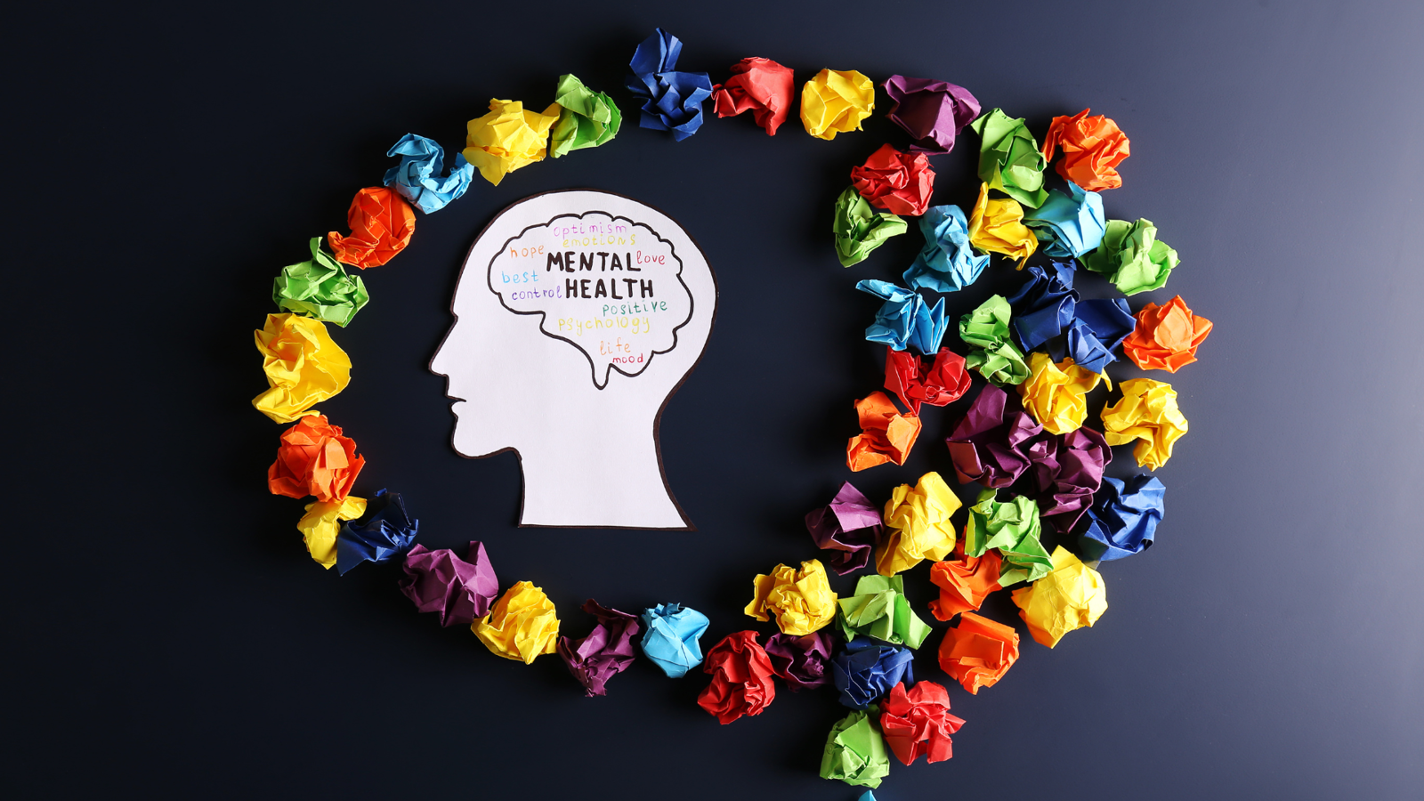 Silhouette of a head with ‘Mental Health’ inside, surrounded by colourful crumpled paper in a heart shape.