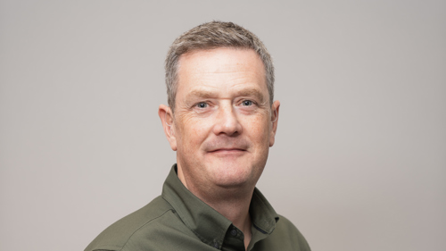 A person with short hair wearing a green button down shirt