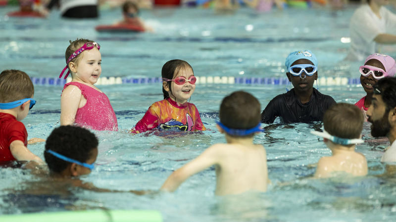 Young swimmers take part in a Learn to Swim session with instructors at a Glasgow Life pool.