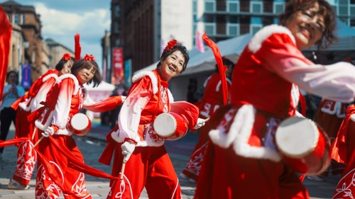 A group of dancers, all wearing red outfits, taking part in an outdoor dance performance on a clear day