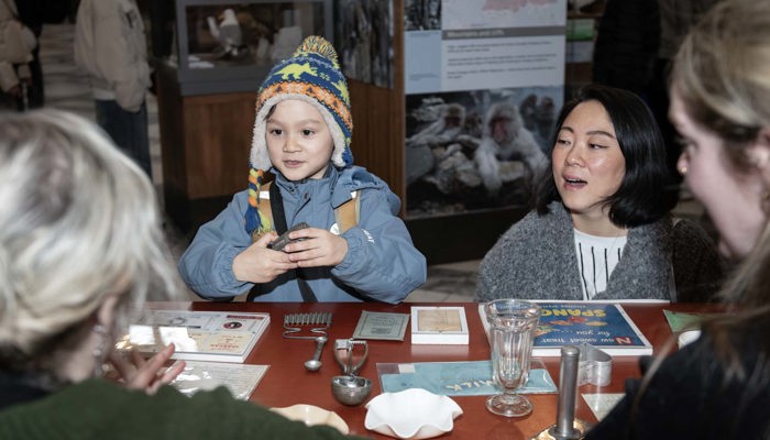 Child examines historic objects at a museum table while taking part in a hands-on activity.