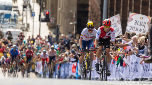 Professional cyclists racing up Montrose Street in Glasgow in front of a cheering crowd during the 2023 UCI Cycling World Championships.
