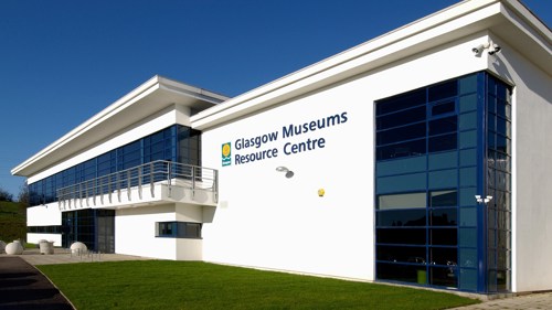 Exterior of a large white building with a flat roof and blue metal window frames