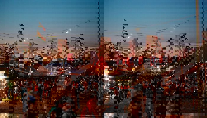 Music fans enjoy an evening performance at a festival as multicoloured flags fly above