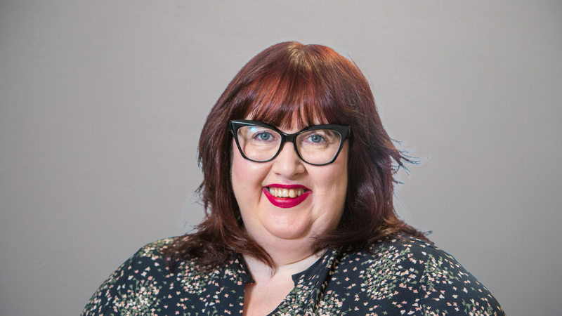 A woman with red hair against a grey backdrop