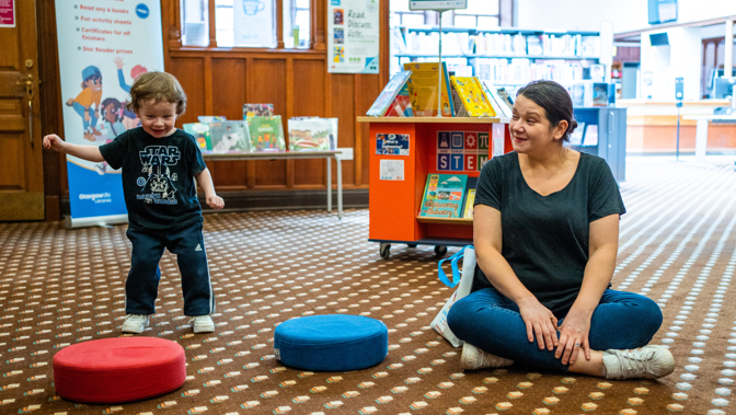 A child and and adult in a library playing an interactive game together